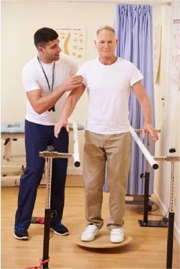 Physical therapist examining man's shoulder during balance exercise in clinical setting