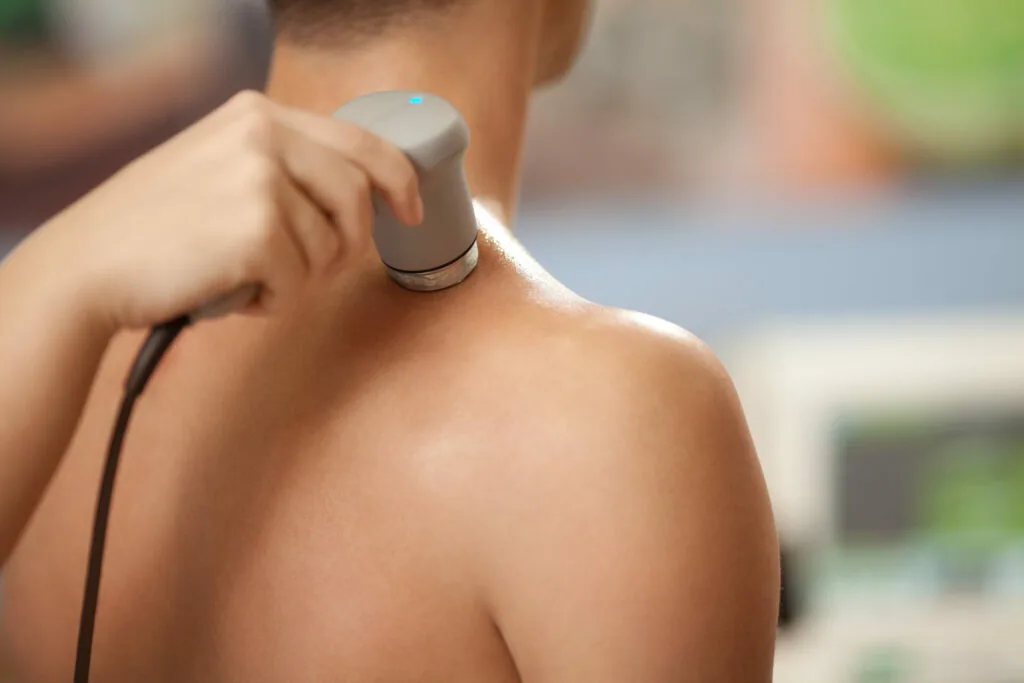 Person applying sunscreen to shoulder outdoors