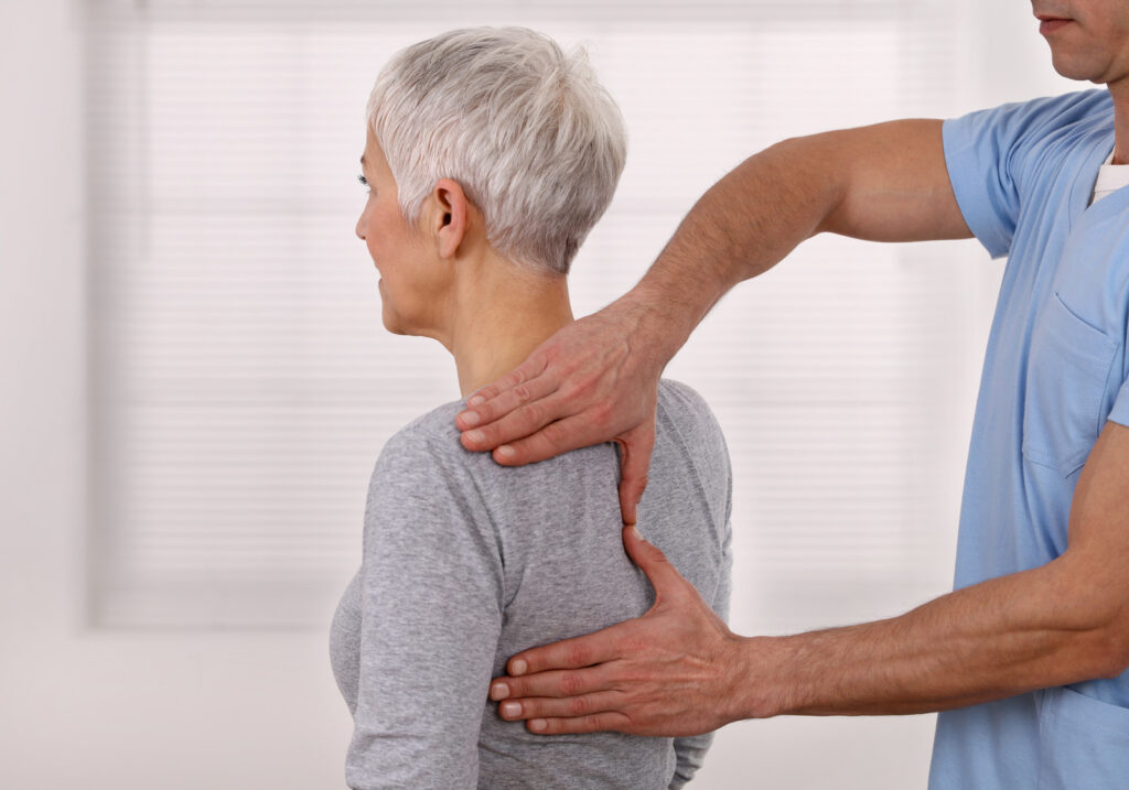 Mature Woman having chiropractic back adjustment. Osteopathy, Physiotherapy, Sport injury rehabilitation concept, holistic care