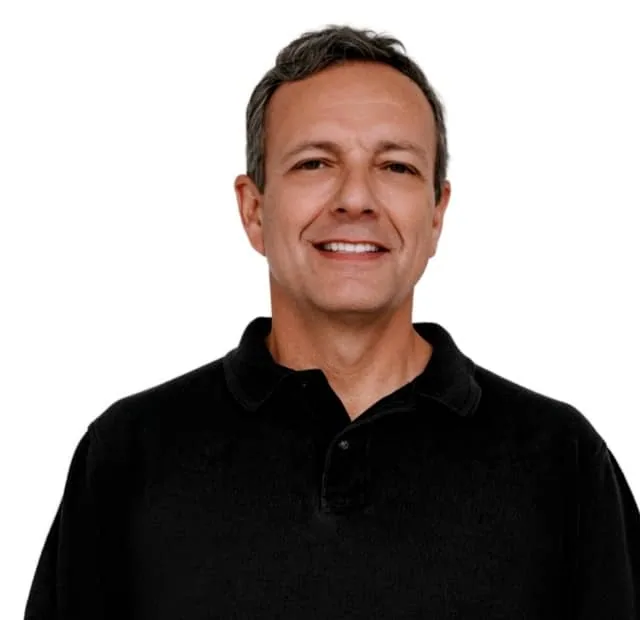Smiling man with dark hair wearing a black polo shirt against a white background